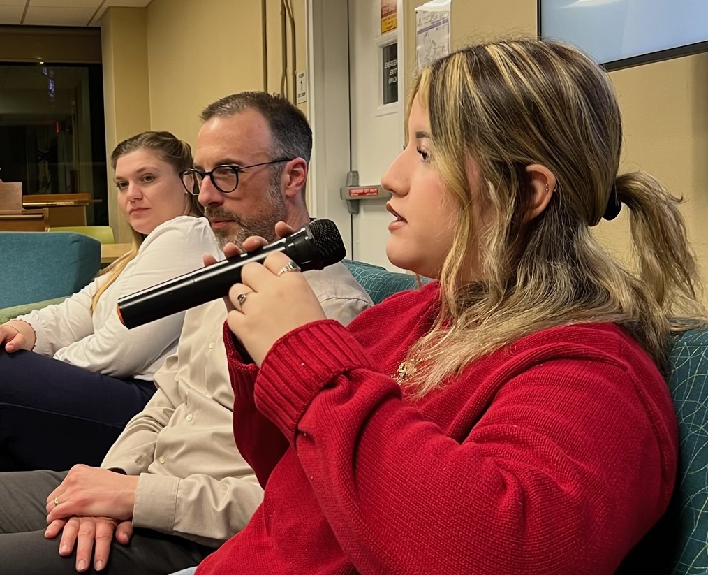 Student speaks on panel, seated beside professor & city clerk